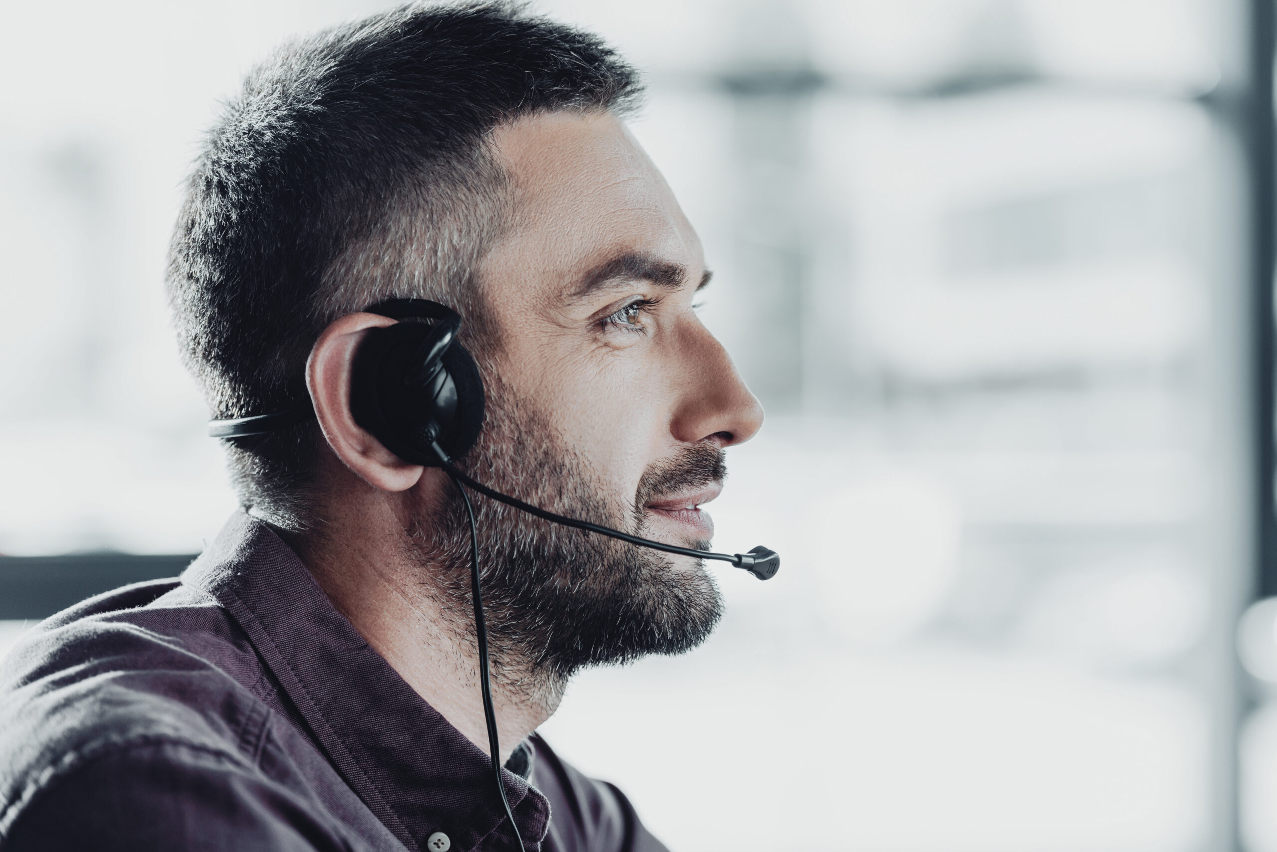 side view of handsome call center worker in headphones with microphone